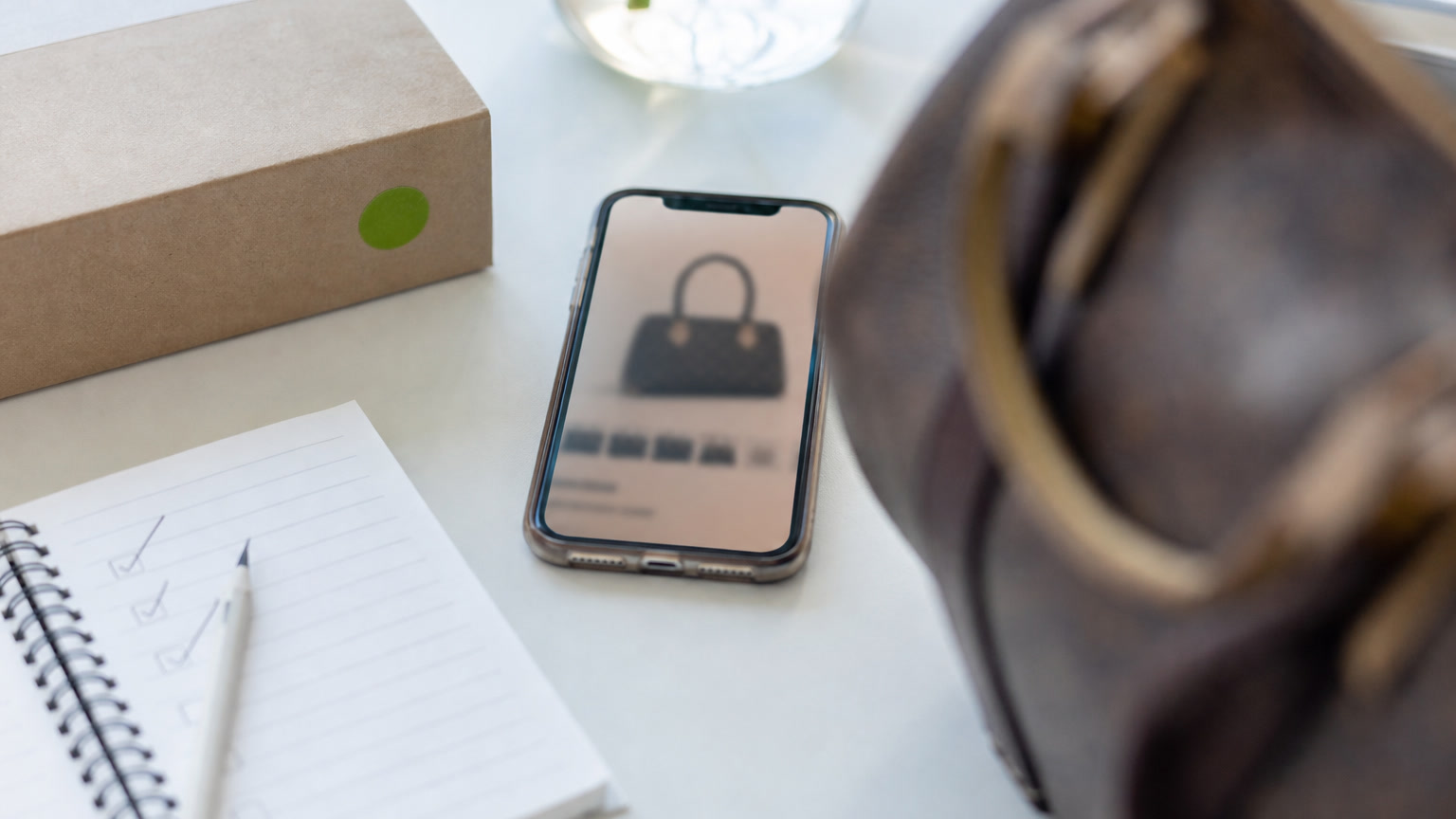 A blurred marketplace listing setup showing a desirable bag, a phone and a checklist, with no readable app text.